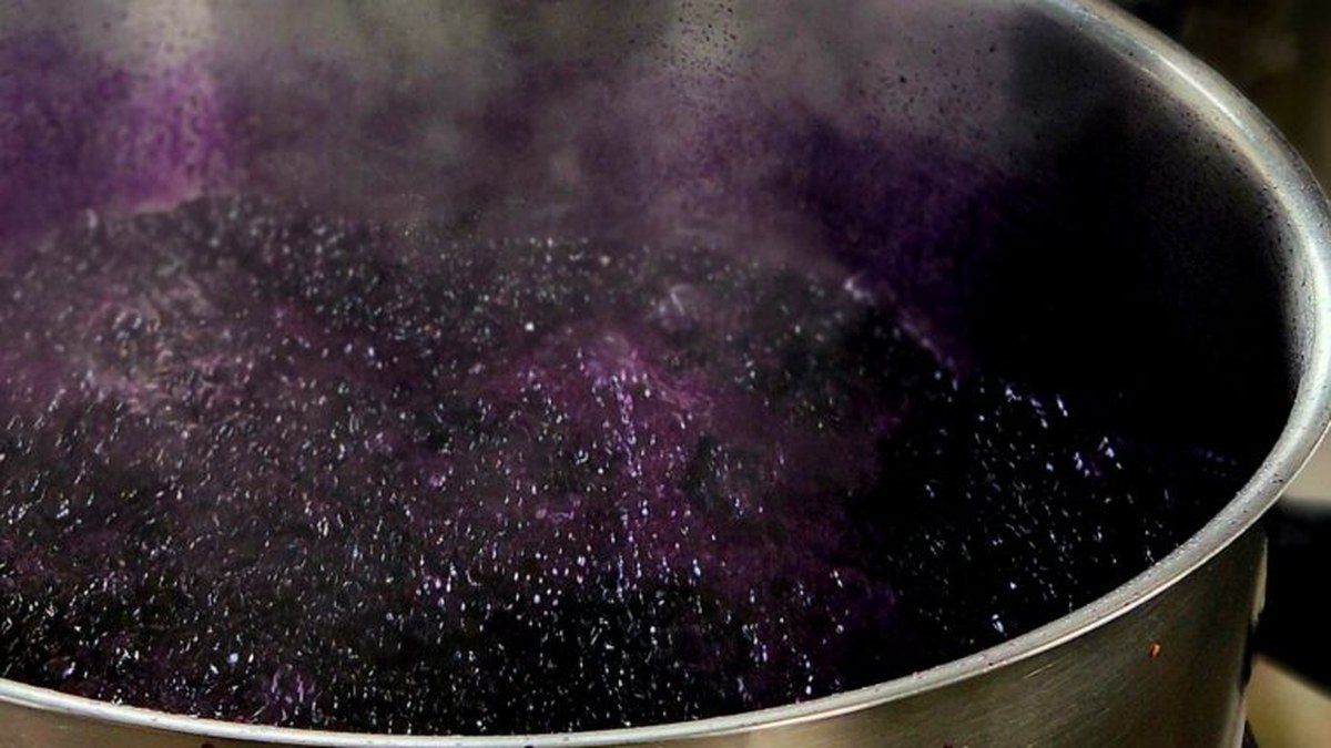 A pot of deep purple nastergal konfyt bubbling and steaming as it cooks in small batches on Bloukop Farm